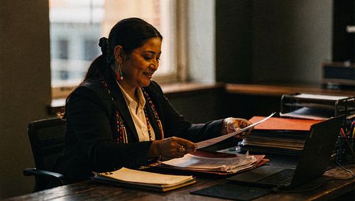Board administrator reviewing governance documents at a desk