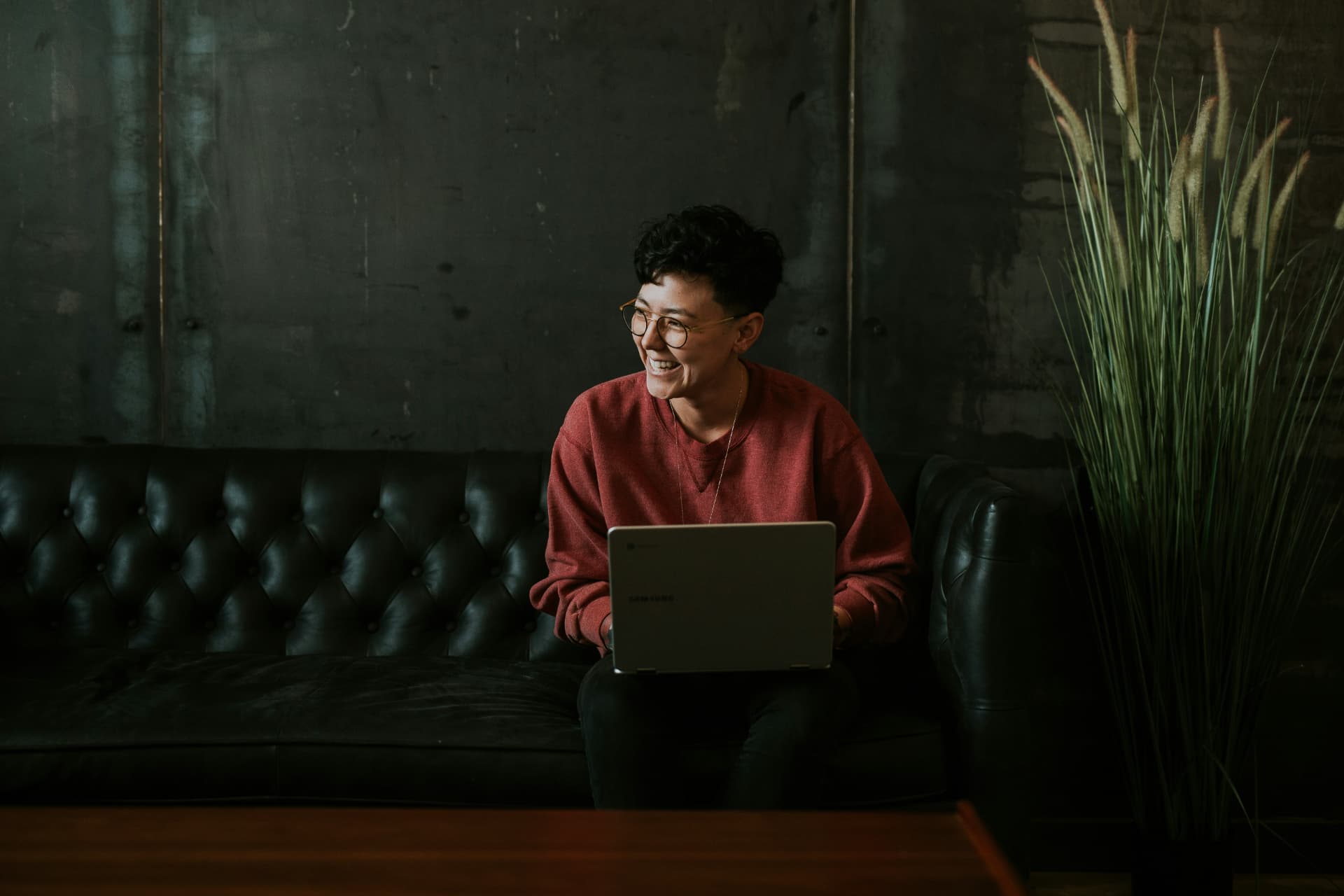 An Indigenous woman smiling while working on a laptop in a boardroom